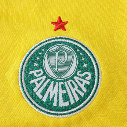 Emblema bordado do Palmeiras em um tecido amarelo vibrante. O escudo é verde e branco com o nome PALMEIRAS e uma estrela vermelha acima.
