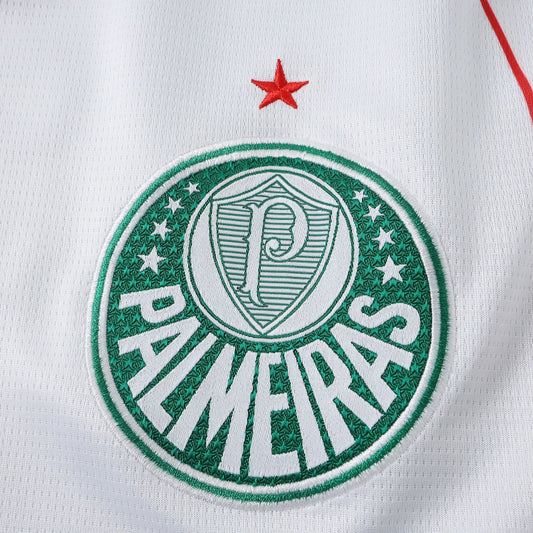 Escudo bordado do Palmeiras em camisa branca, com detalhe de estrela vermelha acima. Escudo verde e branco com o nome PALMEIRAS e a letra P centralizada.