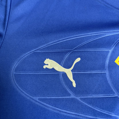 Close lateral destacando o logotipo da Puma em branco, posicionado sobre o tecido azul tecnológico da camisa.