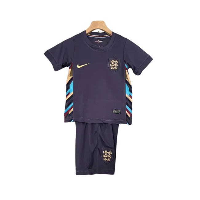 Kit infantil de futebol Inglaterra II 24/25, camisa e shorts roxo escuro com detalhes dourados e listras coloridas nas laterais.