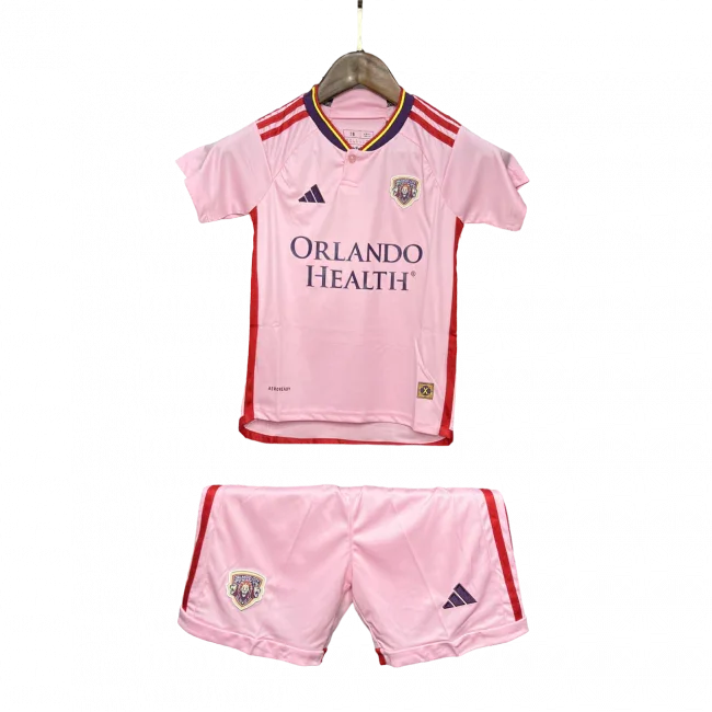 Kit infantil Orlando City II 24/25 rosa, com camisa e shorts. Camisa com escudo do time, logo Adidas e patrocínio Orlando Health.