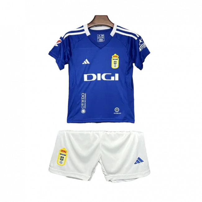 Kit infantil Oviedo I 24/25 completo em fundo preto. Camisa azul com escudo do Oviedo, logo Adidas, patrocínio DIGI e shorts brancos.