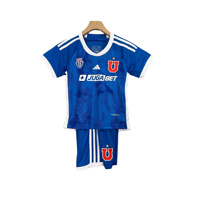 Kit infantil completo da Universidade do Chile, camisa e shorts em tons de azul e branco, com o emblema U e o logo Adidas, pendurado.